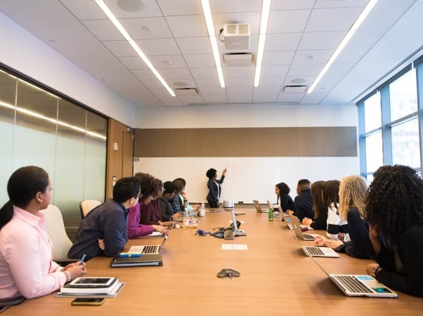 Woman presenting at the front of a meeting room on a whiteboard